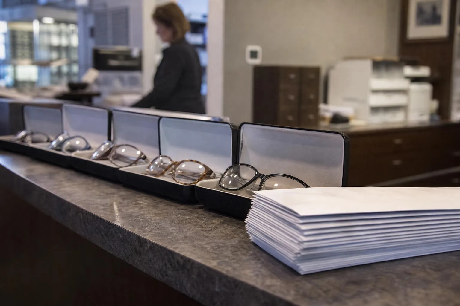 Finished eyeglasses in open cases waiting for pickup on an optical practice front desk