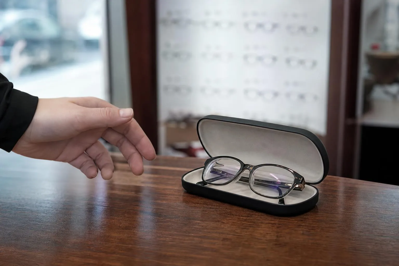 Finished eyeglasses in an open case on an optical practice front desk, ready for pickup