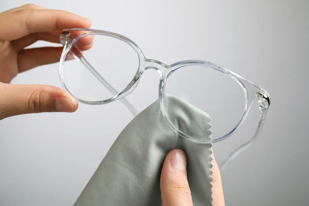 A pair of glasses being cleaned with a microfibre cloth