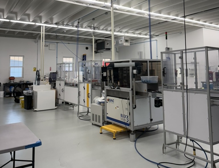 High-Tech Equipment at ITFIT Optical Laboratory - ITFIT Optical Laboratory A clean, modern optical lab workspace at ITFIT Optical Laboratory, featuring advanced lens processing and edging machines arranged in rows under bright ceiling lights – ITFIT Optical Laboratory